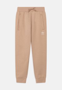 Beige tepláky vyrobené z měkké látky, s páskem na stažení v pase, dvěma postranními kapsami a malým bílým logem Adidas blízko pravé kapsy.