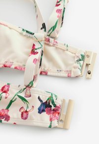 Floral patterned bikini top with adjustable straps and gold metal clasp closures on a white background.