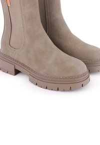 Botas de tobillo de ante marrón con un acabado texturizado, paneles laterales elásticos y una suela de goma gruesa con un patrón de relieve para mayor agarre.