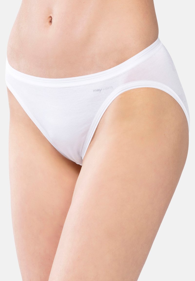 Parte inferiore del torso di una donna che indossa mutande di cotone bianco semplici con il marchio "mey LIGHTS" sul lato, su uno sfondo bianco.