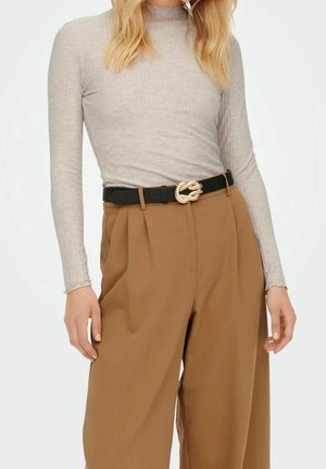 Helle graue Langarm-Ripp-Bluse, kombiniert mit hoch taillierten, gefalteten braunen Hosen. Schwarzer Gürtel mit aufwendiger goldener Schnalle.