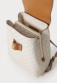 Canvas handbag with beige monogram pattern, tan leather accents, zipper compartment, and a magnetic flap closure. Adjustable strap included.
