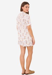 Korte mouwen pyjama set in lichte stof met een speelse print van figuren op een crème achtergrond, inclusief bijpassende shorts.