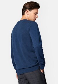 Granatowy sweter z okrągłym dekoltem, wykonany z miękkiego dzianiny, z prążkowanymi mankietami i paskiem w talii. Gładka tekstura z dopasowanym krojem.