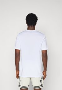Hvid kortærmet t-shirt med rund halsudskæring, glat tekstur og normal pasform, kombineret med lyse atletiske shorts.