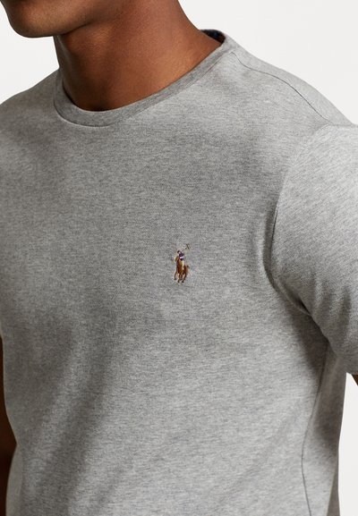 Tricou gri cu guler rotund, realizat dintr-un material moale, având un mic logo brodat cu un cal în zona stânga a pieptului.