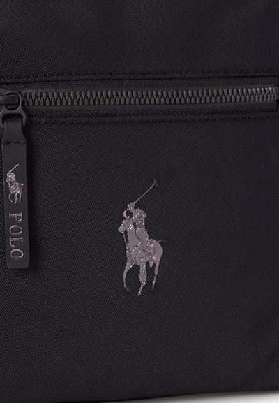 Black fabric bag with a zipper and small silver Polo logo of a horse and rider playing polo on front pocket.