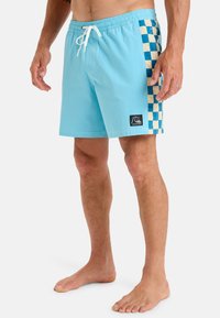 Svetlomodré plavky s kockovaným vzorom v modrej a béžovej farbe na boku. Majú elastický pás so šnúrkou a nášivku s logom.