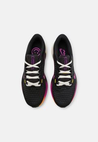 Zapatillas deportivas negras con una parte superior texturizada, cordones blancos y detalles en colores morado, naranja y amarillo. Logo de Nike visible en la lengüeta.
