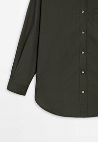 Dunkelgrünes Langarmhemd mit durchgeknöpftem Frontbereich, einer einzigen Brusttasche und abgerundetem Saum. Aus einem glatten Stoff mit einer einheitlichen Textur gefertigt.