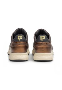 Ruskeat metalliset lenkkarit verkkokankaan yksityiskohdilla, vaaleanbeigeillä pohjilla ja pehmeillä kauluksilla. Kengissä on logo kielekkeessä ja tekstuuri kannassa.