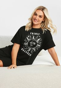 Abito t-shirt oversize nero con una grafica di sole bianco e dettagli facciali, accompagnato dal testo "SOGNATORE COSMICO". Tessuto in cotone morbido.