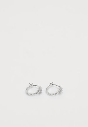 Paire de boucles d'oreilles créoles en argent avec petites pierres transparentes et un ensemble de pierres plus grandes à l'avant sur fond blanc.