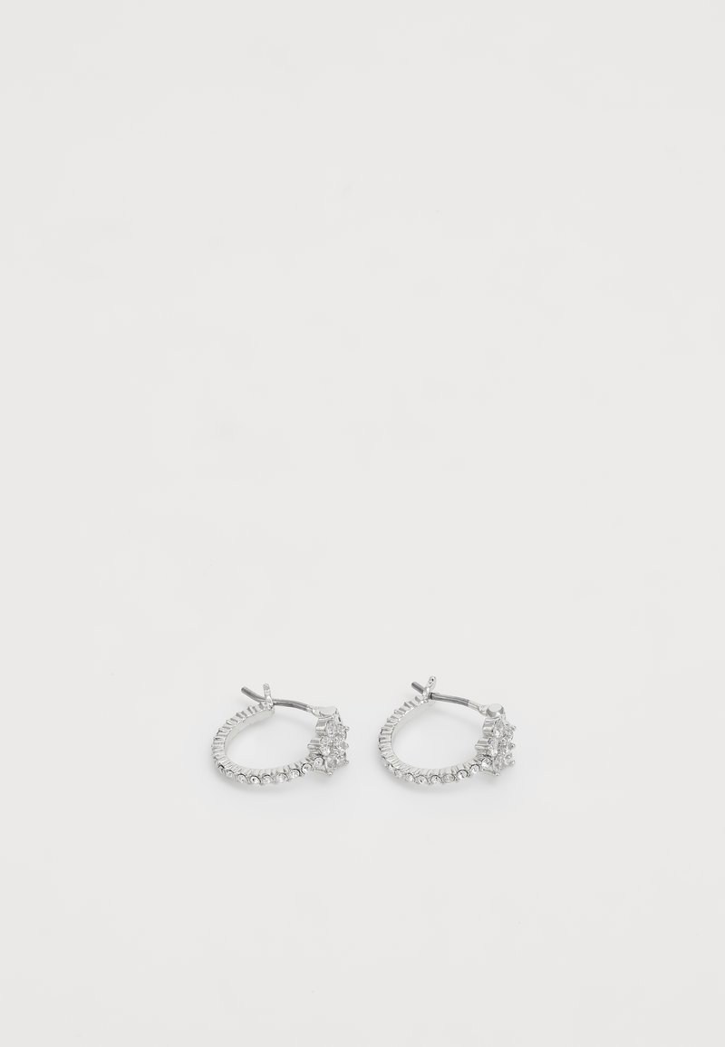 Paire de boucles d'oreilles créoles en argent avec petites pierres transparentes et un ensemble de pierres plus grandes à l'avant sur fond blanc.