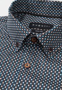 Braune Hemdbluse mit einem geometrischen Muster aus blauen und weißen Quadraten. Hergestellt aus einem glatten Stoff mit einem Kentkragen und Knopfakzenten.