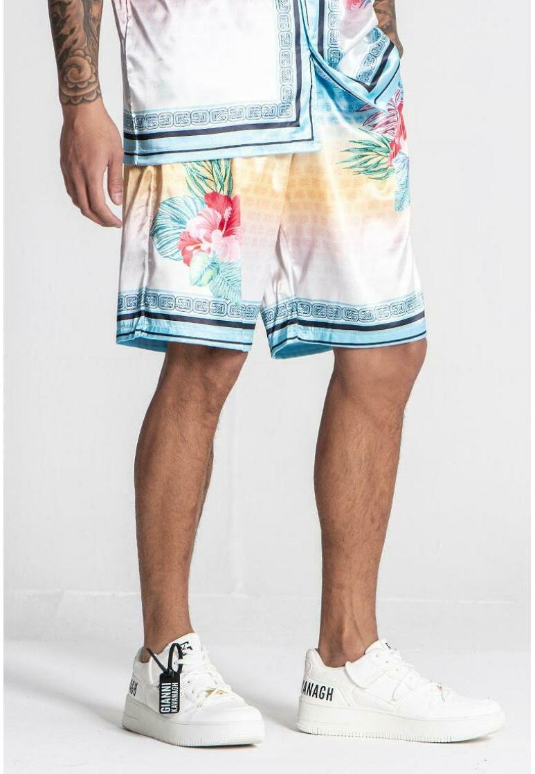 Herre blomstrede shorts i glossy stof, med et blåt og pink tropisk mønster og en blåkantet kant, parret med hvide sneakers.