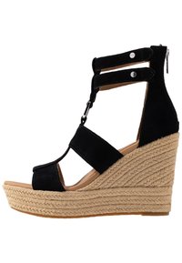 Czarne zamszowe sandały na koturnie mają wiele pasków i odkryty przód, z plecionym juteowym obcasem i zapięciem na zamek z tyłu.