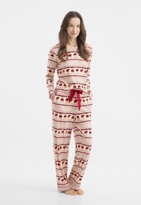 Pajama set v červené a krémové barvě se vzorem, dlouhými rukávy, kulatým výstřihem, páskem na stahování a měkkou tkaninou s vánočním motivem.