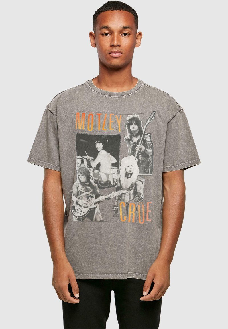 Grå oversized t-shirt med et vintage sort-hvidt grafisk motiv af rockbandmedlemmer, med orange "MÖTLEY CRÜE" tekst på forsiden.