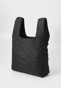 Sac fourre-tout matelassé noir avec un motif ondulé unique, grande ouverture en haut et en matériau nylon doux. Design robuste et léger.