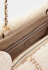 Borsa di colore crema con texture trapuntata, rifiniture in morbido pellicciotto sintetico, tracolla in catena con finitura dorata e scomparti interni con motivo logo.