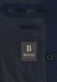 Dunkelblaues Innenfutter eines Anzugs mit Boggi Milano Etikett, innerer Brusttasche und vierlochnähtigem Knopf auf der rechten Seite.