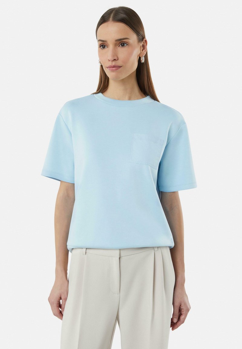 Lichtblauwe katoenen T-shirt met een ronde hals, korte mouwen en een borstzak. De stof heeft een soepele textuur en een relaxte pasvorm.