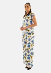 Conjunto floral de dos piezas que incluye una camiseta de manga corta con flores azules y naranjas sobre un fondo blanco, combinada con pantalones de pierna ancha a juego.