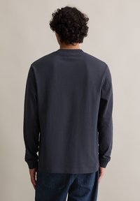 Koszula z długim rękawem w ciemnoszarym kolorze z bawełny, z okrągłym dekoltem i żebrowanymi mankietami, charakteryzująca się prostym i czystym wzornictwem bez wzorów.