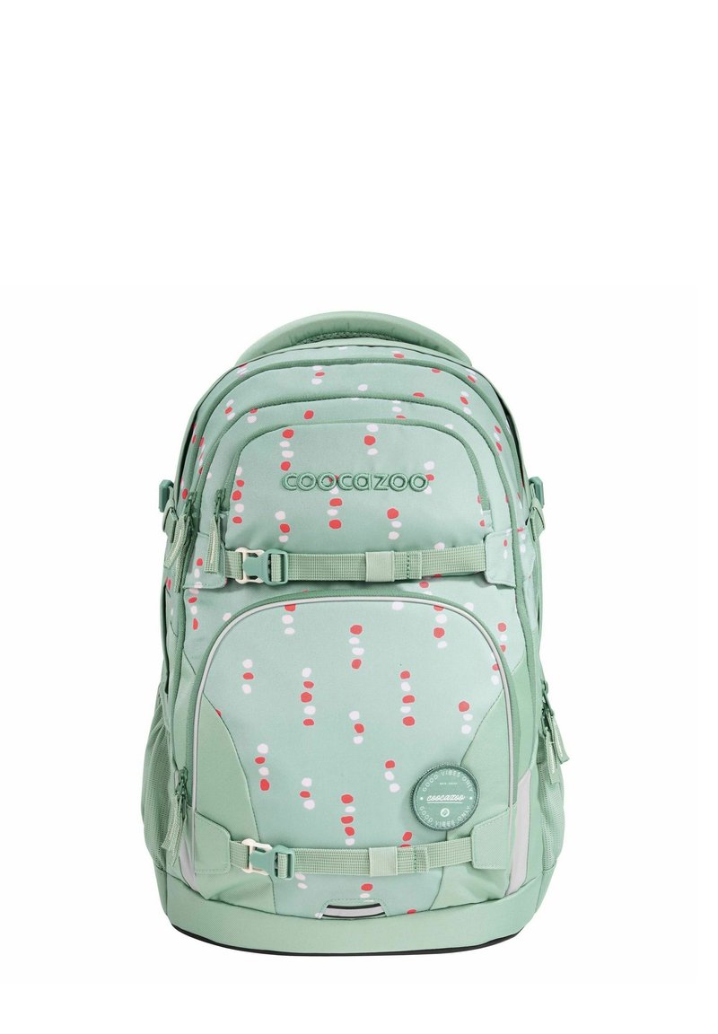 Green backpack with a polka dot pattern in red and white. Features zippers, straps, and a round logo patch. Soft fabric with padded grips.