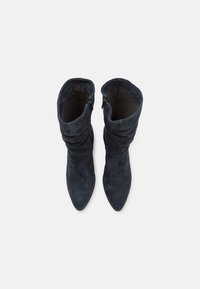 Dark blue suede ankle boots with a pointed toe, feature slouchy upper and side zippers for easy wear. Soft inner lining texture.