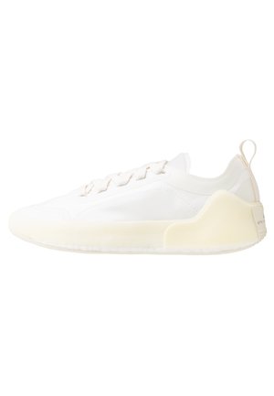 Biały niskopodbiegowy sneaker z zapięciem na sznurowadła, grubą, kremową podeszwą i pętelką na pięcie, pokazany z profilu na białym tle.