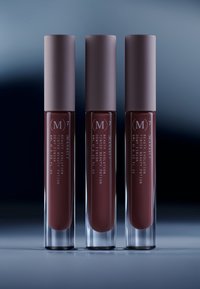 Kolme sylinterimäistä nestemäisen huulipunan putkea, joissa on mattapintaiset laventelinväriset kannet ja läpinäkyvät rungot. Sisältö on syvän viininpunainen sävy.