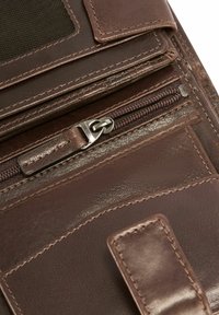 Brązowy skórzany portfel z zamykaną na zamek komorą, gładką fakturą oraz składanym klapą z widocznym przeszyciem i metalowymi elementami.