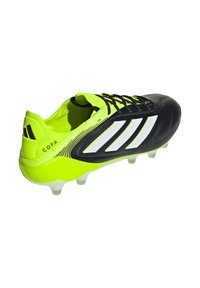 Crampon de soccer Adidas Copa noir et jaune fluo avec des rayures blanches et des lacets noirs, présenté sous un angle latéral-supérieur.