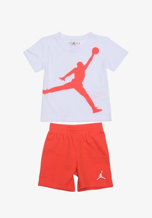 T-shirt blanc à manches courtes avec une grande silhouette rouge d'un joueur de basketball et un short rouge assorti avec un petit logo blanc de joueur sur la jambe gauche.
