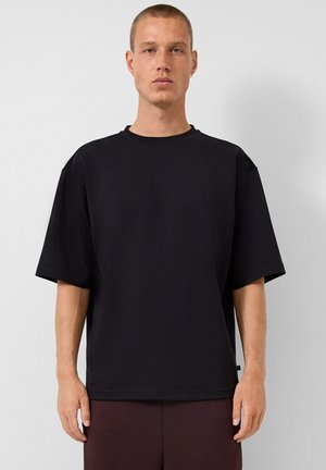 T-shirt noir à manches courtes en coton, avec une coupe décontractée, un col rond et un logo de marque subtil à l'avant.