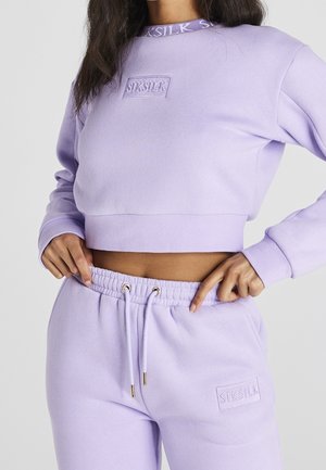 Femme portant un sweat-shirt court violet clair SikSilk et un pantalon de survêtement assorti avec une taille à cordon.