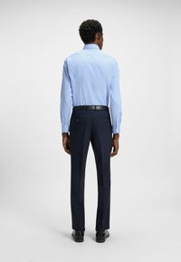 Ljusblå randig skjorta med långa ärmar och knappmanschetter, tillsammans med mörkblå byxor. Enkelt design, skräddarsydd passform, formell look.