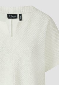 Haut blanc texturé à manches courtes avec un col en V discret et une étiquette noire à l'intérieur du col indiquant S. Oliver Black Label.
