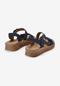Blue sandal with multiple straps, featuring a buckle and a beige platform sole. Smooth material with slight sheen. Rear view.