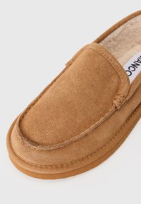 Brune ruskinds slip-on sko med et blødt indersål, syet detaljer og en flad gummisål. Enkel design med en afrundet tå.