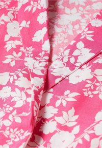 Tela rosa con un patrón floral blanco, que presenta varias flores y hojas. La textura parece suave y liviana. Los bordes están bien doblados.