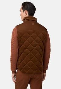 Gilet imbottito marrone con colletto alto, realizzato in corduroy testurizzato; presenta maniche a maglia a trecce in una tonalità di marrone più chiara e una patch con il logo.