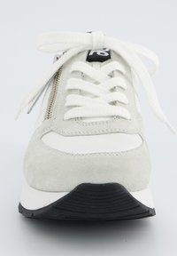 Basket en suédine grise avec des accents blancs, bout rond, semelle texturée, lacets plats et une fermeture éclair en métal sur le côté.