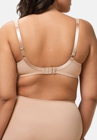 Sostenedor beige claro con tirantes de satén ajustables y un cierre de gancho en la parte posterior. La textura suave y el diseño sin costuras destacan la comodidad.