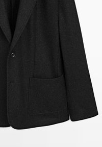 Schwarzer Woll-Blazer mit einem Ein-Knopf-Verschluss, einem Reverskragen und einer aufgesetzten Tasche auf der linken Seite für funktionale Details.