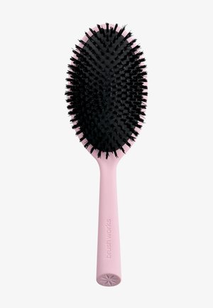 Brosse à cheveux rose avec des poils noirs, tête ovale, et l'inscription "brushworks" en relief sur le manche sur fond blanc.