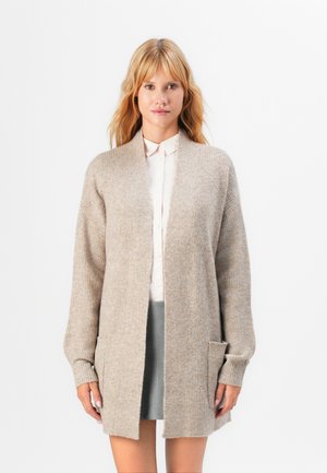 Beige wool blend cardigan with an open front, ribbed texture, side pockets, and long sleeves. Styled over a light shirt and skirt.