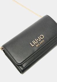Borsa a tracolla nera in ecopelle testurizzata con logo dorato e tracolla a catena. Presenta una chiusura a patta e un design rettangolare elegante.